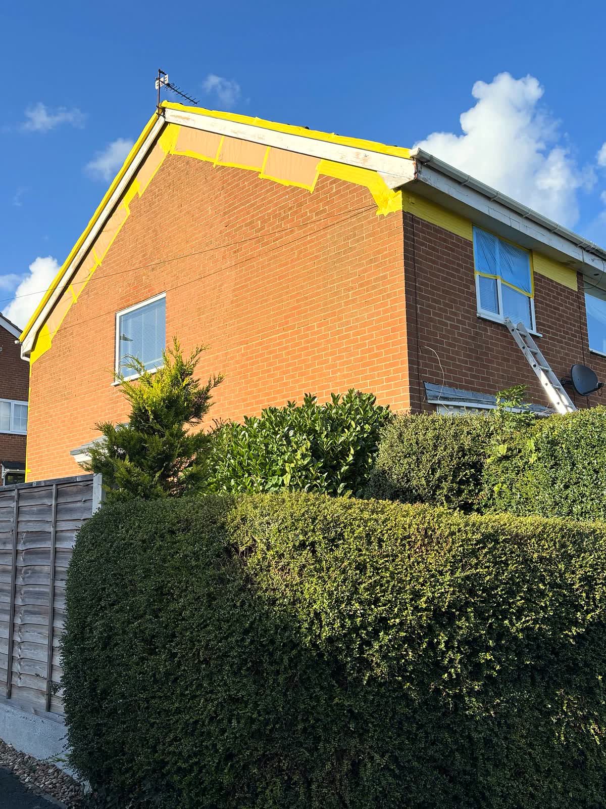 Brick house with fascias and gutters masked for a respray in traffic white