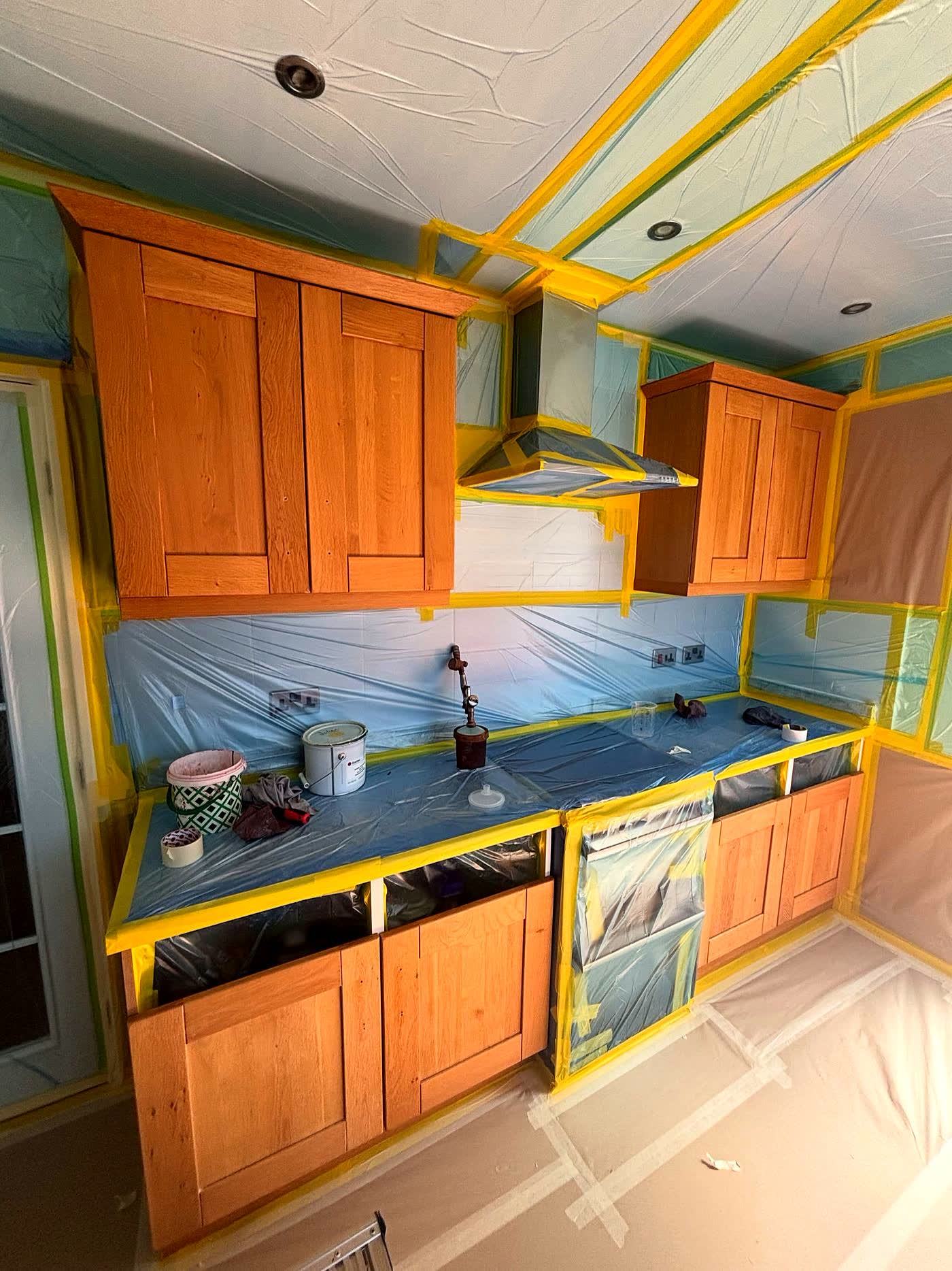 Oak kitchen cabinets masked and prepped in place for a respray