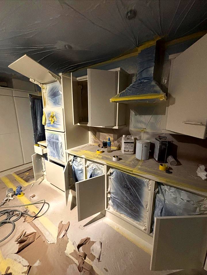 Kitchen cabinets and doors being sprayed on site with the room fully masked