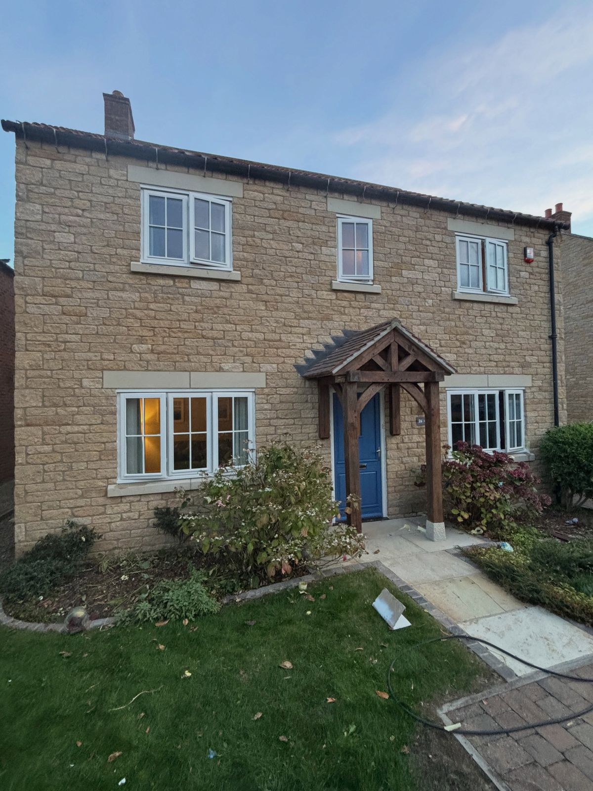 The finished house in the evening with the lights on behind the cream windows
