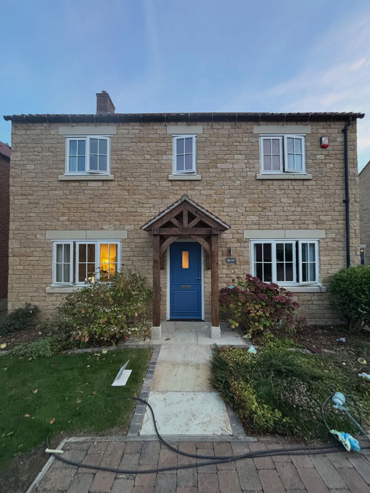 The finished house from the front, windows in cream and the blue front door